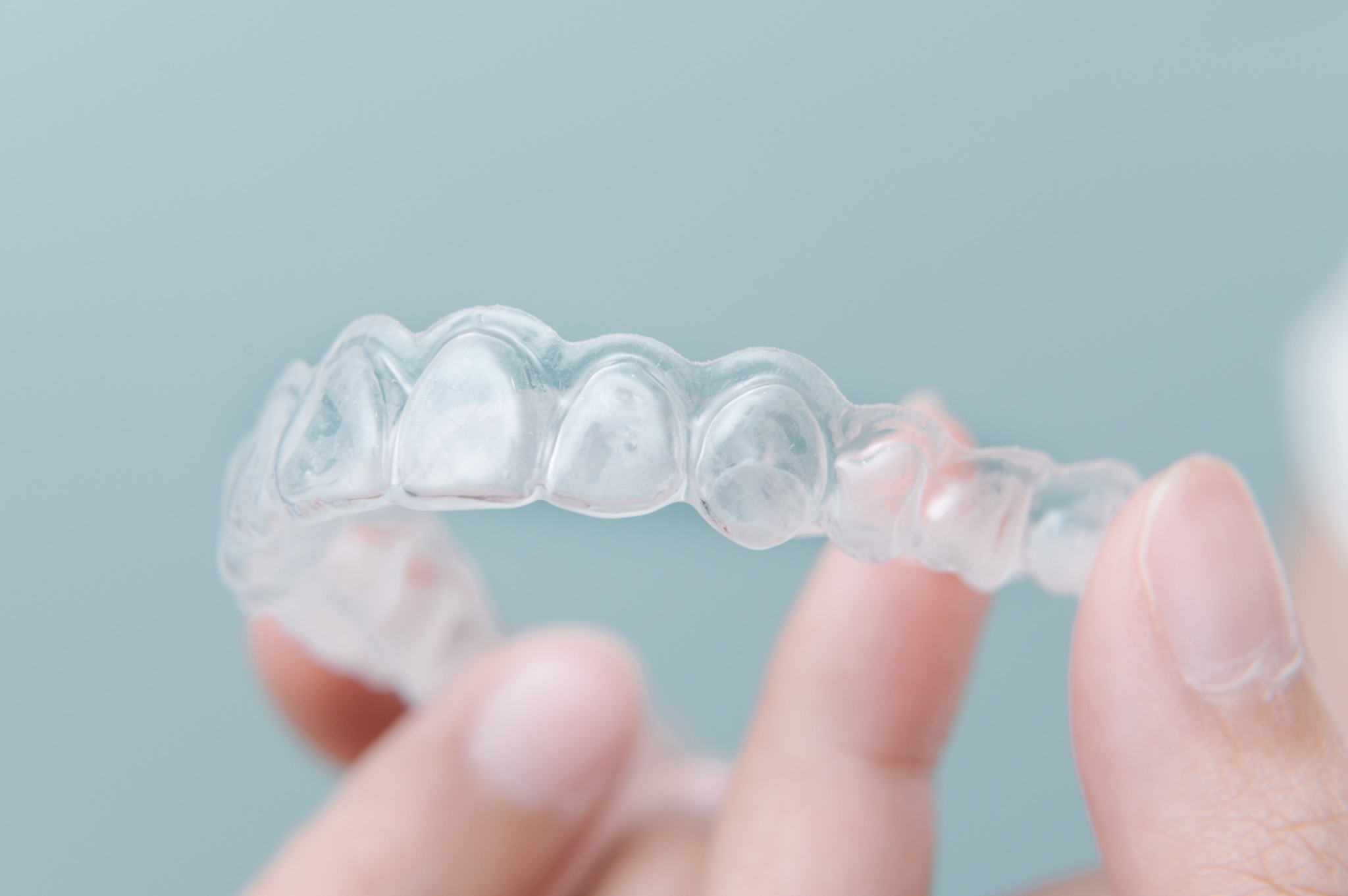 Real clear retainer held between fingertips